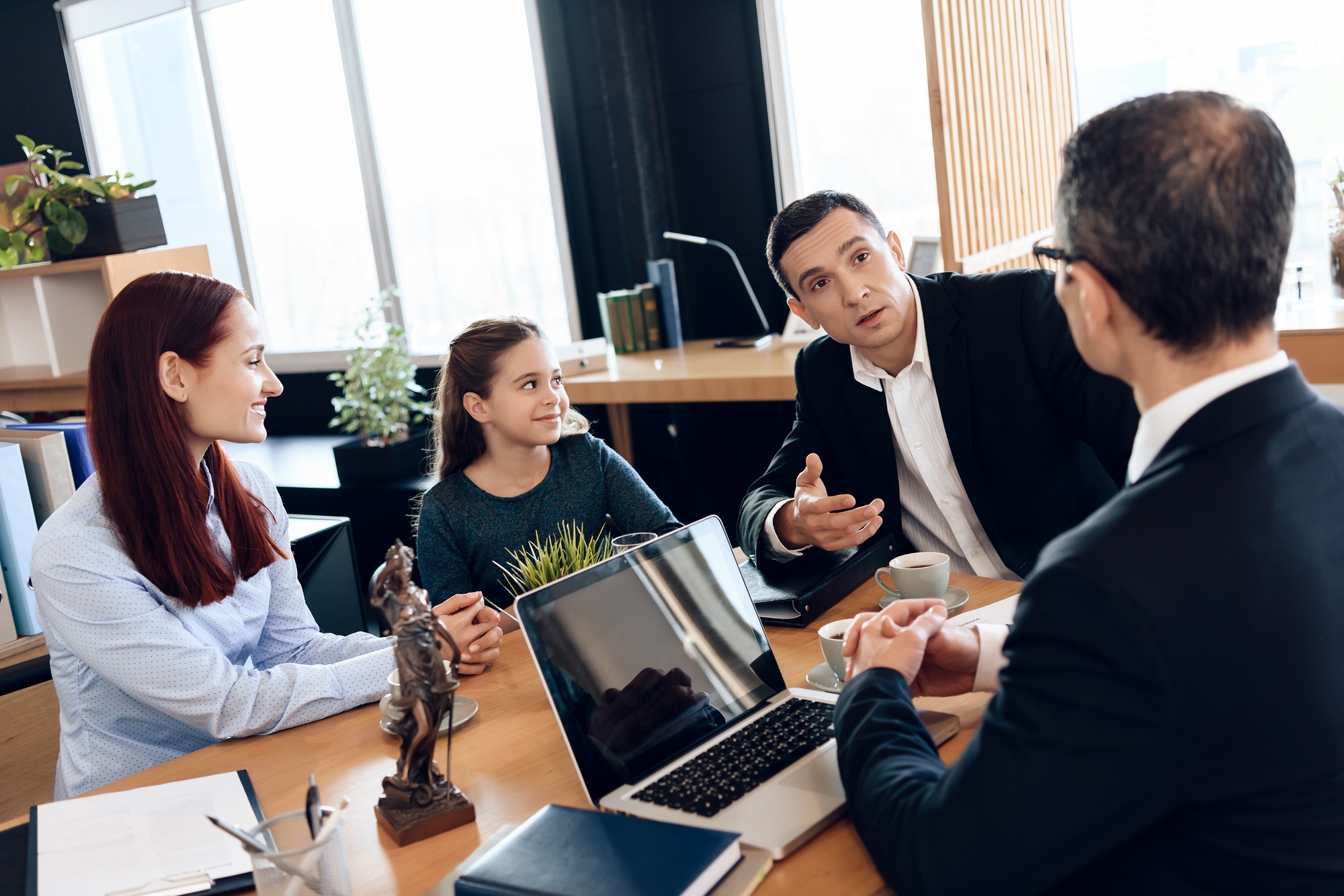 Adult Father, Red Head Mother and Little Smiling Daughter Are Sitting in Lawyer’s Office. Family in Office of Family Lawyer.